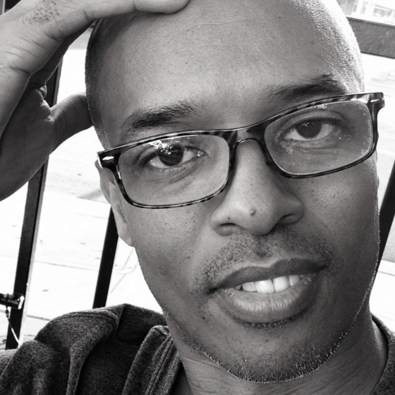Black-and-white portrait of Ray Brown wearing glasses.